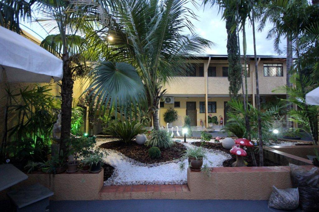 un patio con palmeras y plantas frente a un edificio en Pousada Rozam, en Olímpia