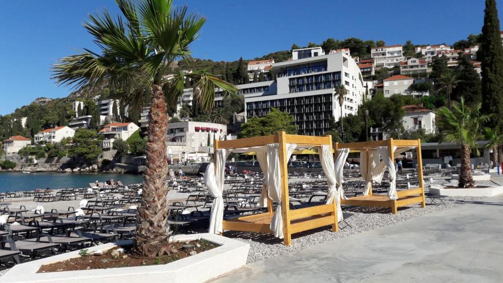 a beach with tables and chairs and a palm tree at Ana Guesthouse in Dubrovnik