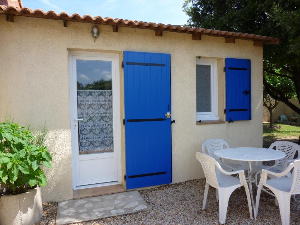una casa con puerta azul, mesa y sillas en Bourgarel, en Vidauban
