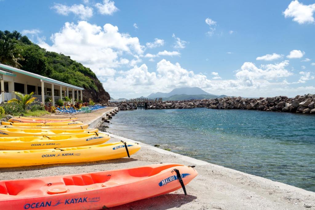 a row of kayaks on a beach next to the water at Bird Rock Beach Hotel in Basseterre