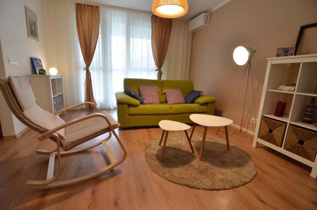 ein Wohnzimmer mit einem grünen Sofa und 2 Tischen in der Unterkunft AVA Apartments ADORA FOREST 1 in Timişoara