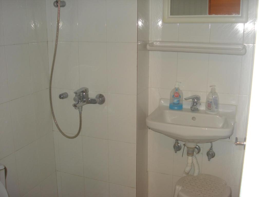biała łazienka z umywalką i prysznicem w obiekcie Apartment city center w mieście Patras