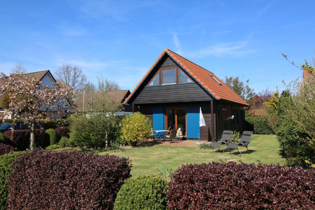 een huis met een rood dak en stoelen in een tuin bij Ferienhaus 3 Köhr-Eickhoff in Lembruch