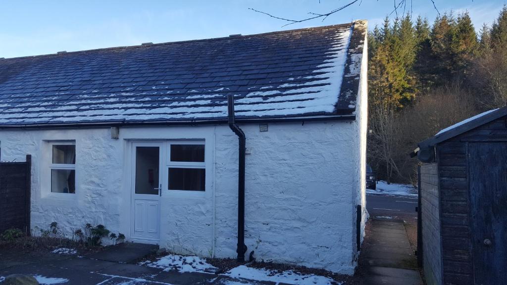 a white shed with a door and a roof at Silver Ridge, 2 House O` Hill in Newton Stewart