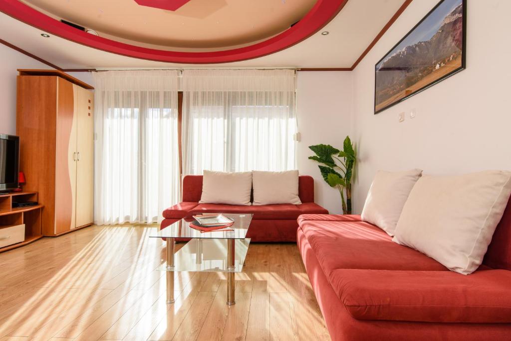 una sala de estar con 2 sofás rojos y una mesa de cristal. en Apartments Sofija, en Trogir