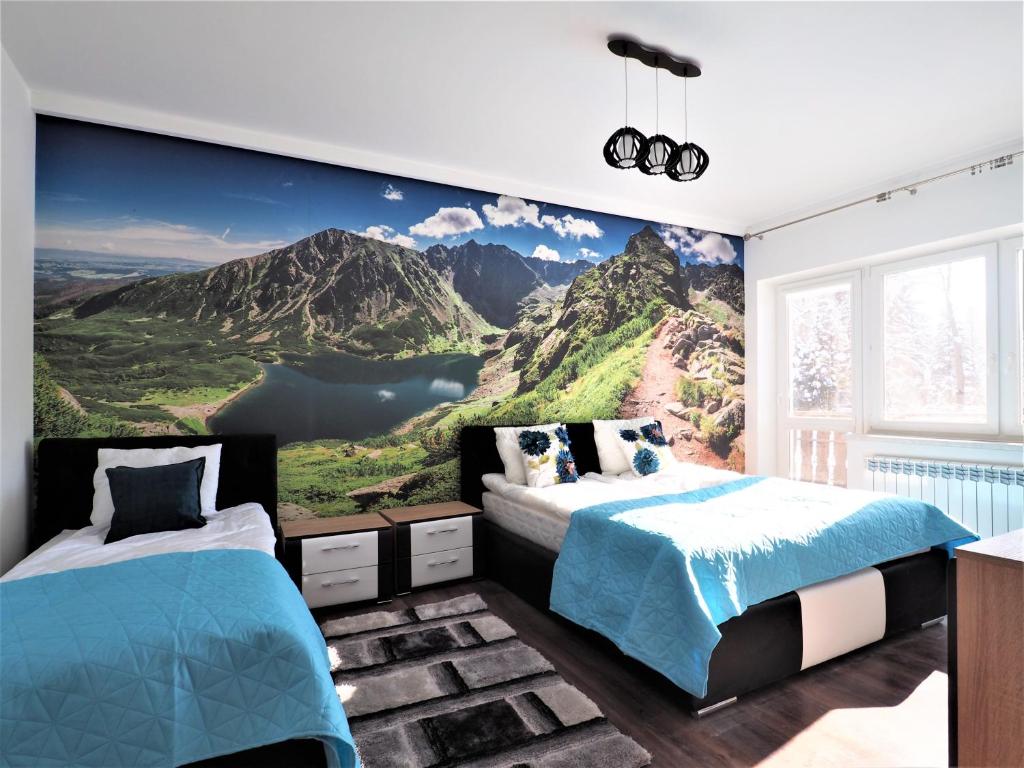 1 Schlafzimmer mit 2 Betten und einem Wandbild aus den Bergen in der Unterkunft VIP Apartamenty KRUPÓWKI in Zakopane