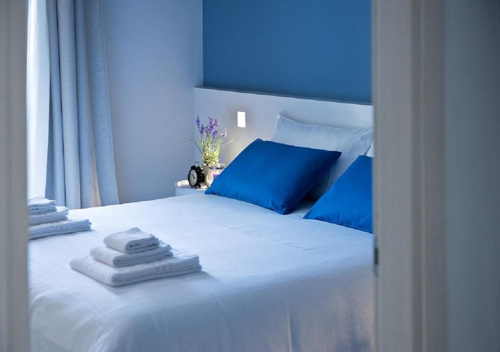 a white bed with blue pillows and towels on it at Bacio di Dama Lingotto in Turin