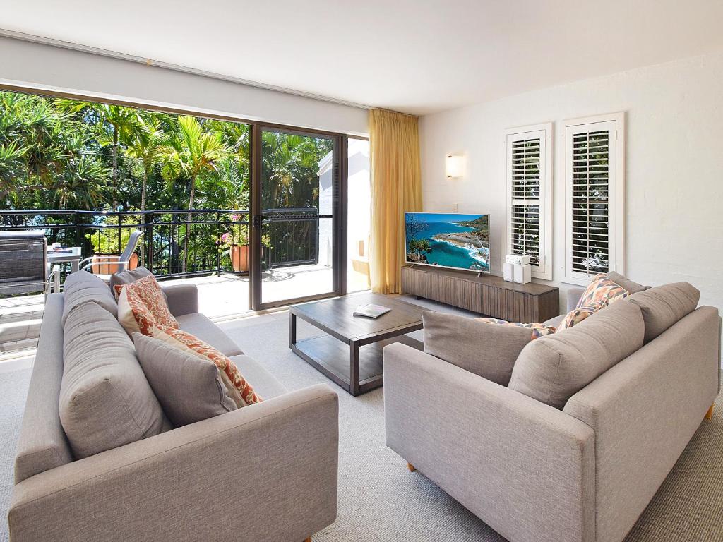 a living room with two couches and a television at Bayona Apartments in Noosa Heads