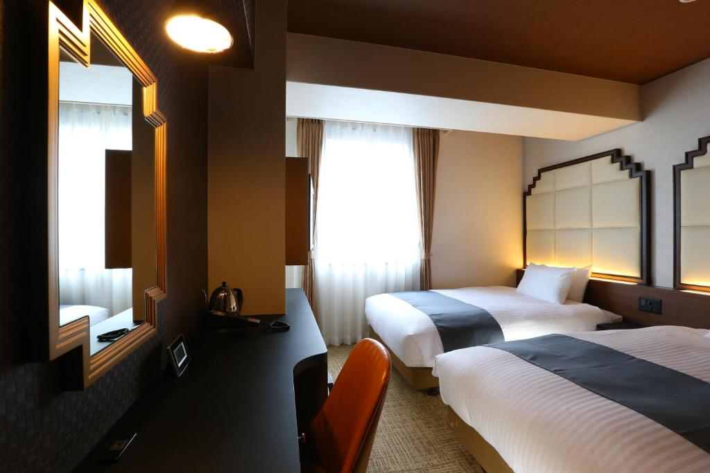 大阪市にあるホテルウィングインターナショナル セレクト大阪梅田のベッド2台と鏡が備わるホテルルームです。