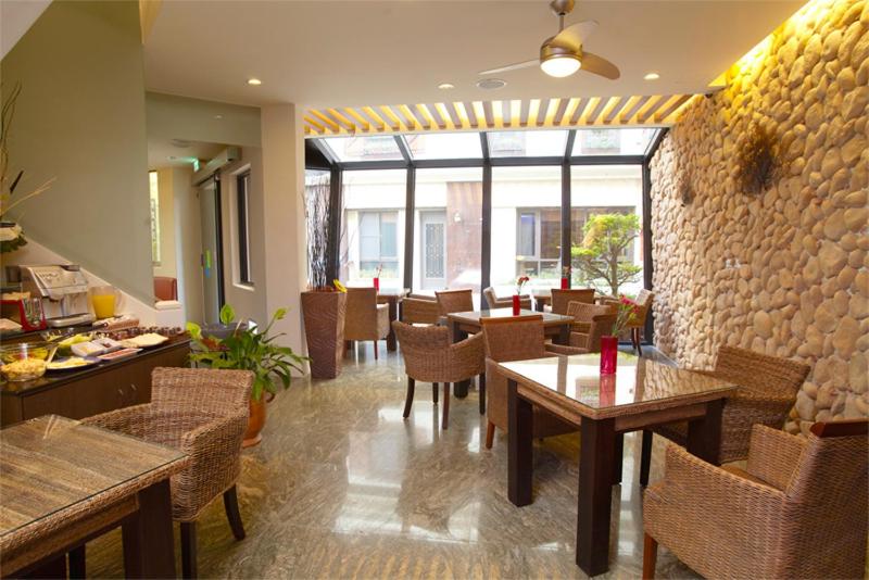 a restaurant with tables and chairs and a stone wall at Haiye Guest House in Kenting