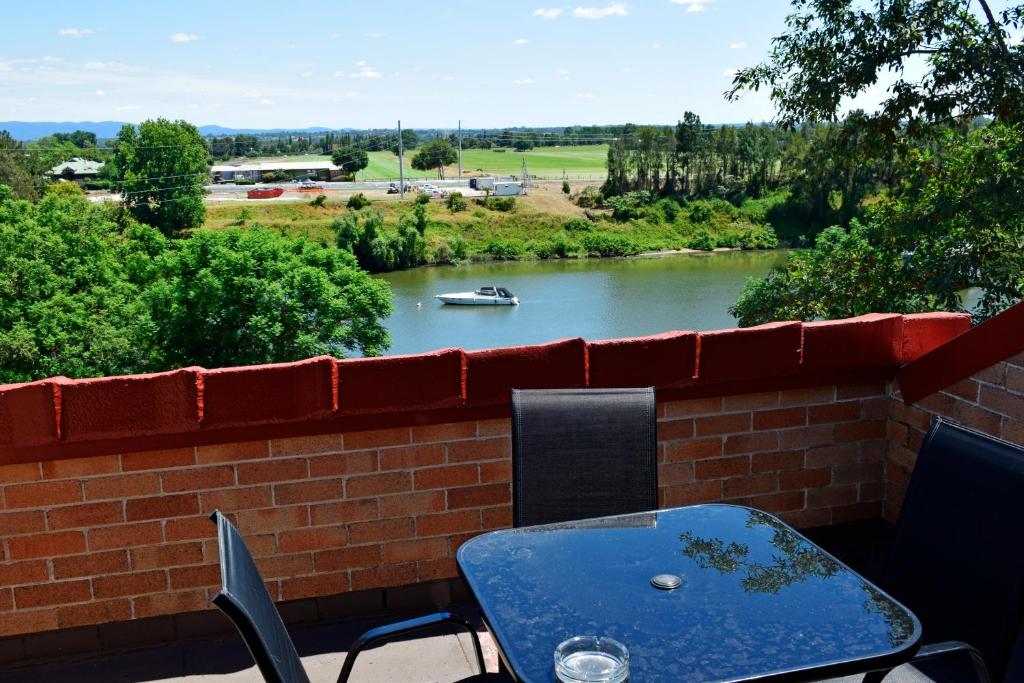 een tafel en stoelen op een bakstenen muur met uitzicht op een rivier bij Windsor Terrace Motel in Windsor