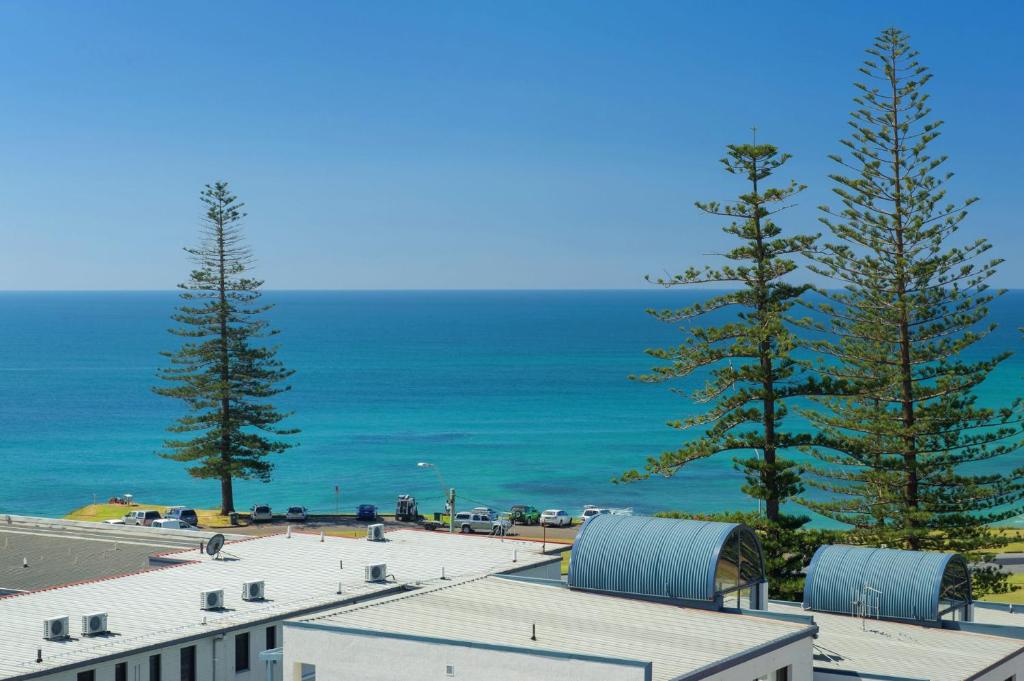 uma vista para uma praia com árvores e o oceano em Akuna 20 6 Joffre Street em Port Macquarie
