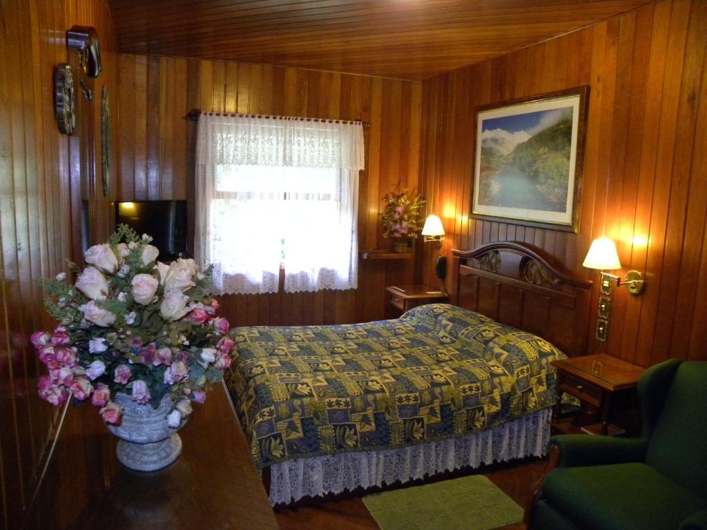 1 dormitorio con 1 cama y un jarrón de flores sobre una mesa en Hotel Akaskay, en Nova Friburgo