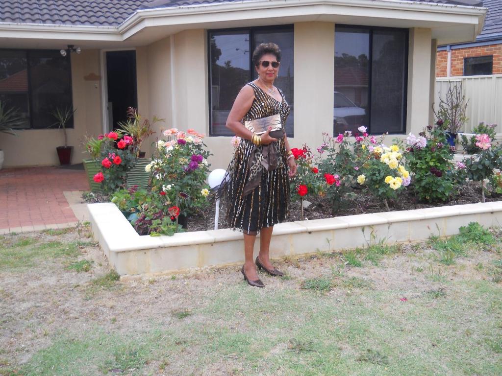 uma mulher em pé em frente a um jardim de flores em Mimi's House em Perth