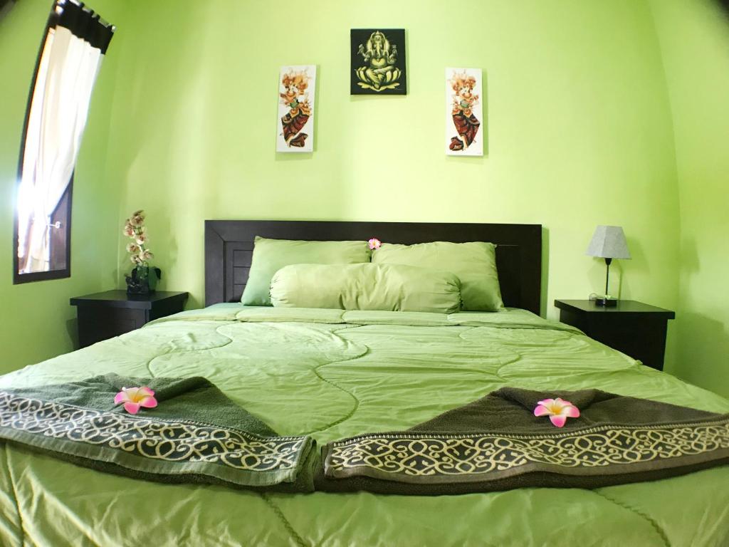 een groene slaapkamer met een groot bed met bloemen erop bij Tegal Homestay in Sanur