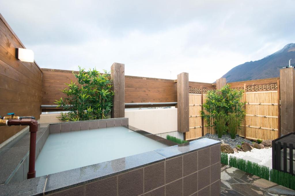 a backyard patio with a pool and a fence at ETAVIA Yufuinekimae in Yufuin