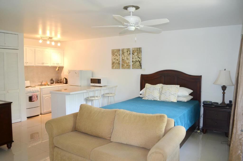 a bedroom with a bed and a couch and a kitchen at One Love Cozy Studio Seawind On The Bay in Montego Bay