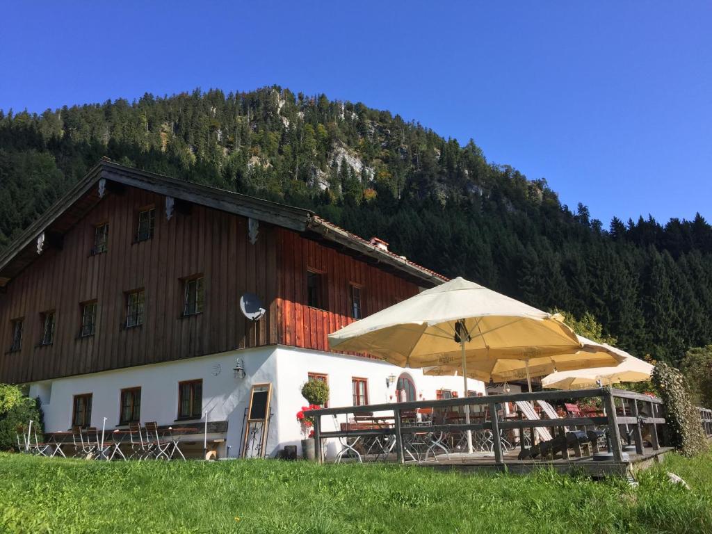 ein Gebäude mit Tischen und Sonnenschirmen davor in der Unterkunft Berggasthof Butzn Wirt in Ruhpolding