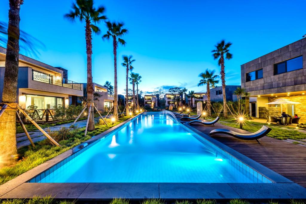 a swimming pool with palm trees and a building at Arts Spa&Poolvilla in Jeju