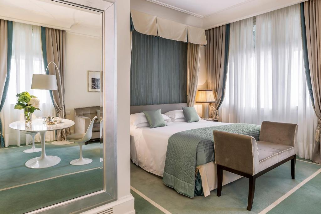 a bedroom with a bed and a table and a chair at Savoia Excelsior Palace Trieste - Starhotels Collezione in Trieste