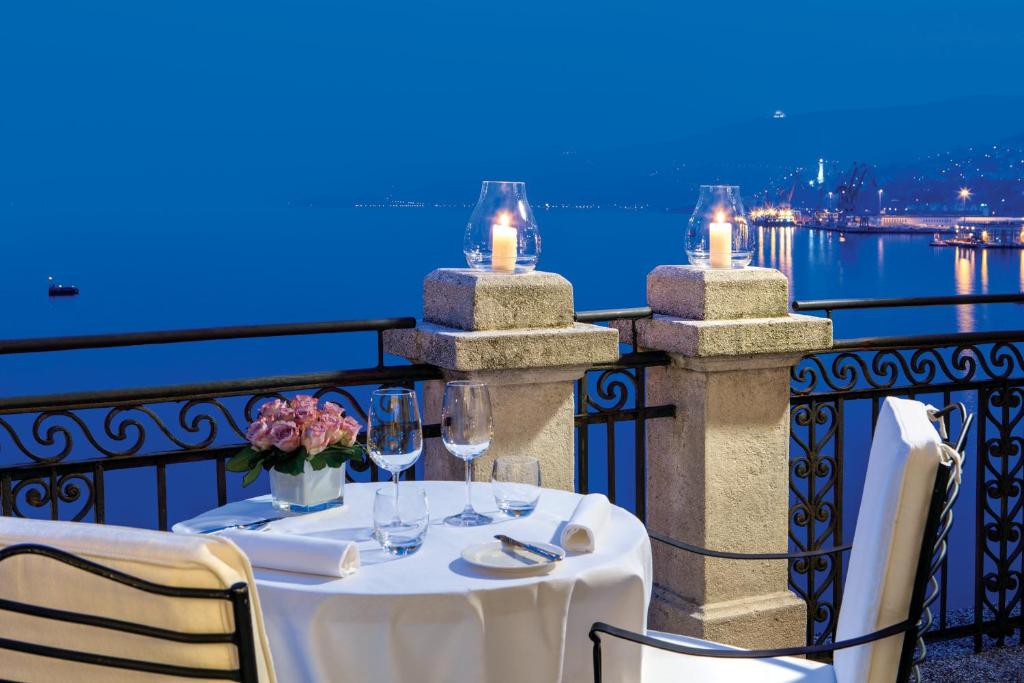 a table with wine glasses and flowers on a balcony at Savoia Excelsior Palace Trieste - Starhotels Collezione in Trieste