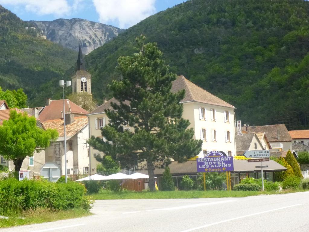 una città tra le montagne con una chiesa di Hôtel Restaurant Les Alpins a Saint-Julien-en-Beauchêne