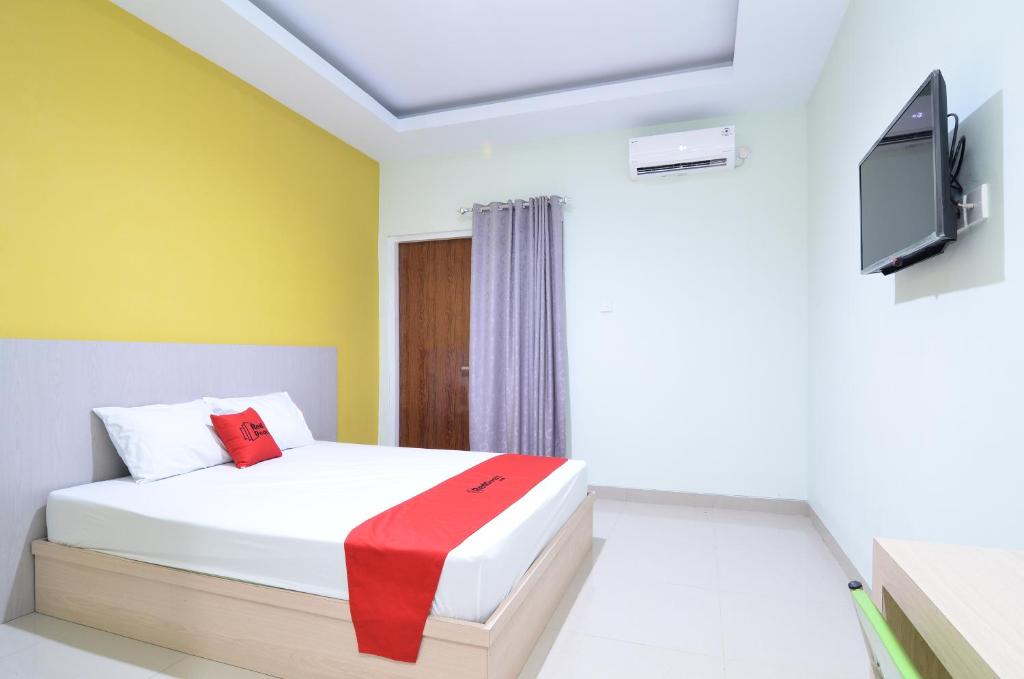 um quarto com uma cama e uma televisão de ecrã plano em RedDoorz near Museum Keraton Surakarta em Surakarta