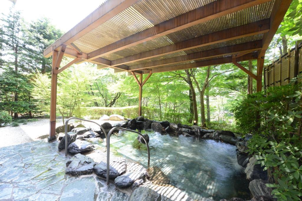 Hotel Harvest Kinugawa في نيكو: حوض استحمام ساخن تحت بيرجولا خشبي