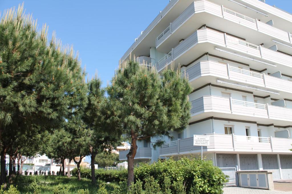 アルバ・アドリアティカにあるAppartamenti Stella Marinaの目の前に木々が生い茂る白いアパートメント