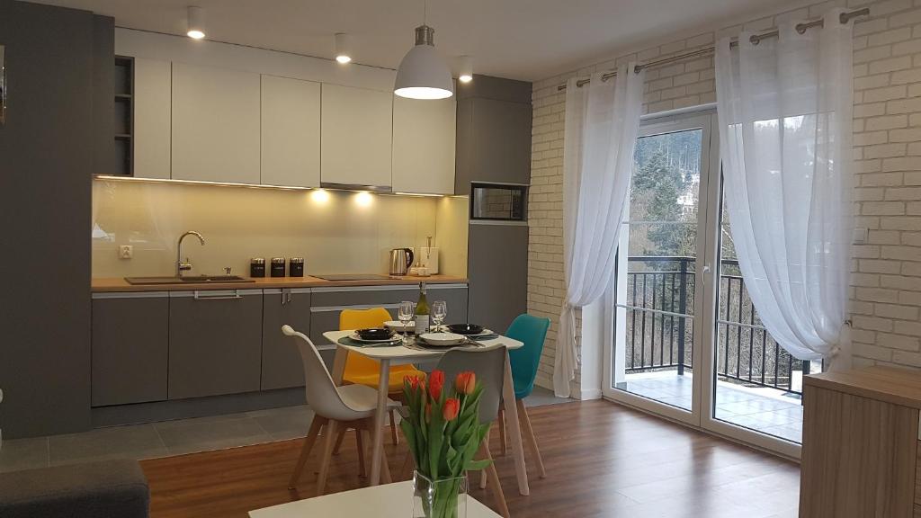a kitchen and living room with a table and chairs at Apartament Juzo in Szklarska Poręba