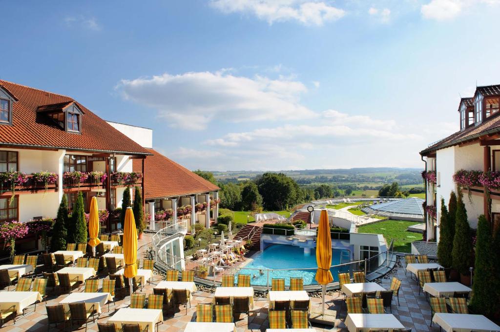 a view of a hotel with a pool and tables and umbrellas at Hotel Fürstenhof - Wellness- und Golfhotel in Bad Griesbach
