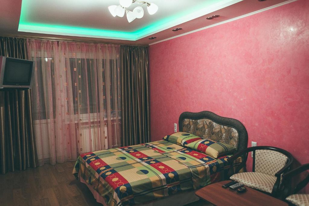 - une chambre avec des murs roses, un lit et une télévision dans l'établissement Prime Home, à Tchernihiv