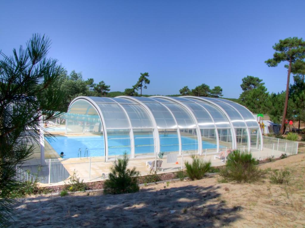 una gran piscina en una casa de cristal en Village Vacances Les Dunes - Domaine de Bombannes, en Carcans