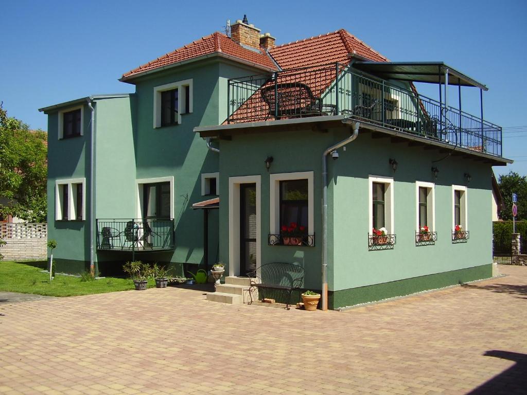 a green house with a balcony on top of it at Penzion Večerka in Lednice