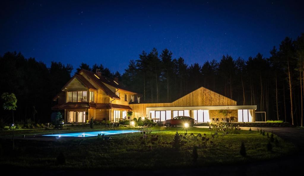 a house with a pool in front of it at night at Leśna Chata in Cieszanów