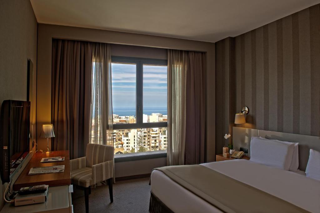 ein Hotelzimmer mit einem Bett, einem Schreibtisch und einem Fenster in der Unterkunft ParkTower Suites in Beirut