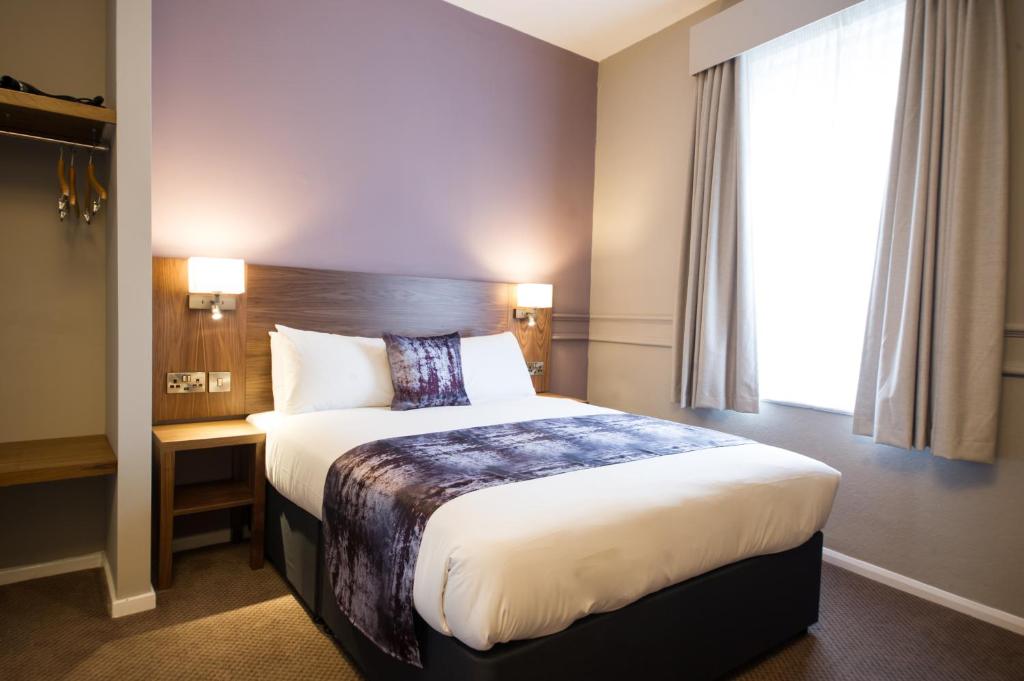 a hotel room with a large bed with a window at The Town House by Innkeeper's Collection in Norwich