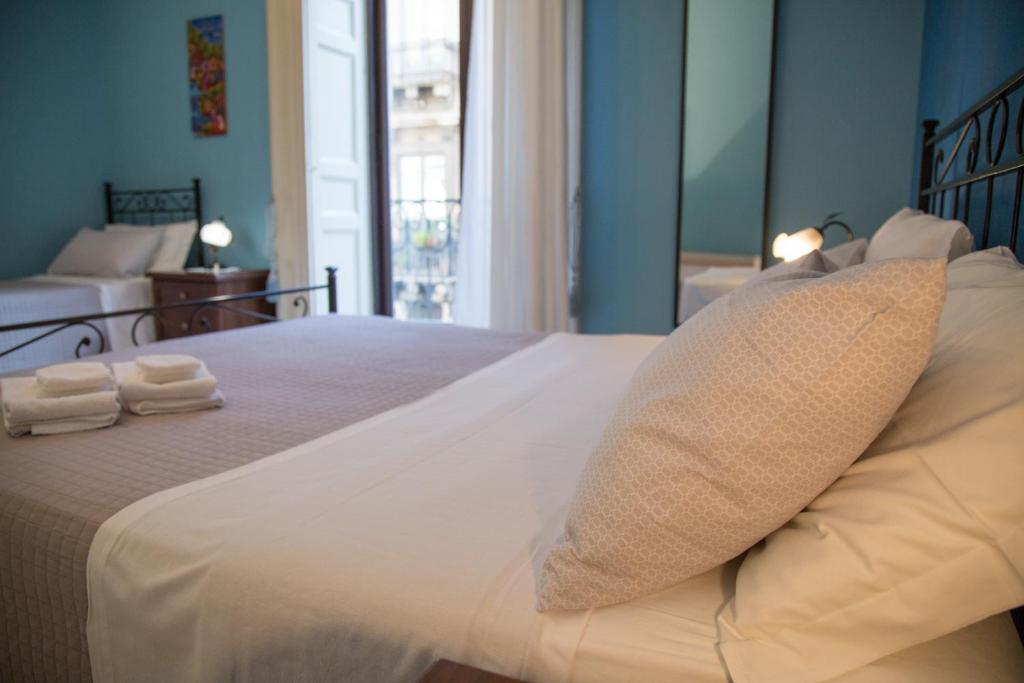 a bedroom with a large white bed with towels on it at Catania Inn Rooms in Catania