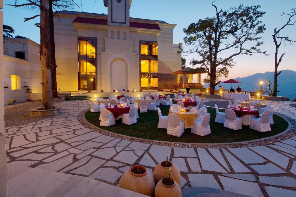 un grupo de mesas y sillas frente a un edificio en Royal Orchid Fort Resort Mussoorie, en Mussoorie