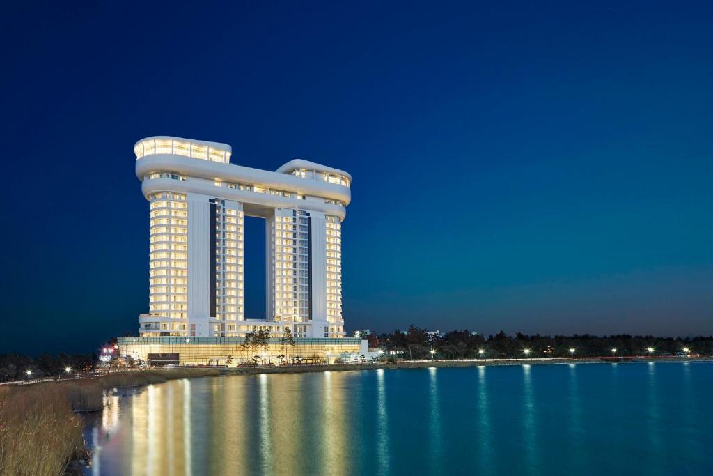 un grand bâtiment sur l'eau la nuit dans l'établissement Skybay Hotel Gyeongpo, à Gangneung