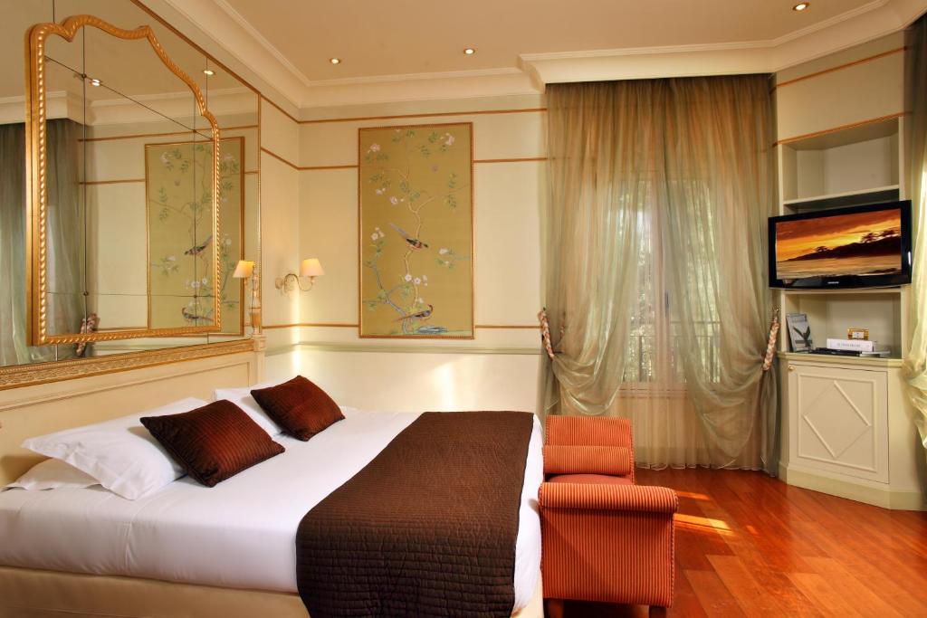 sypialnia z łóżkiem, krzesłem i telewizorem w obiekcie Hotel Degli Aranci w Rzymie