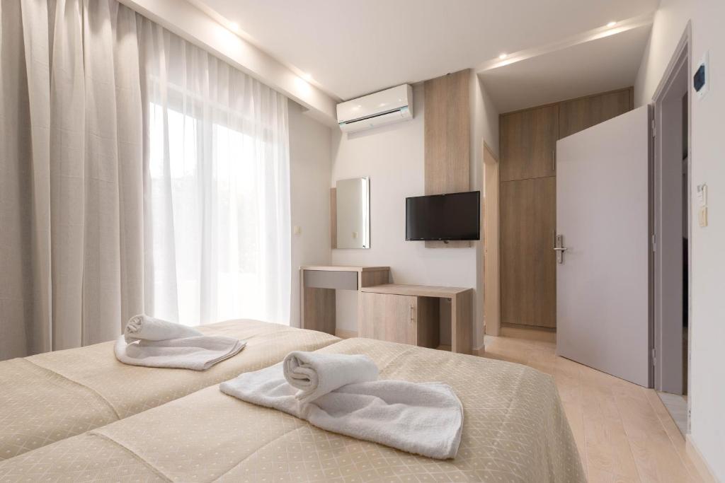 a bedroom with two white towels on two beds at Saint George Resort in Archangelos