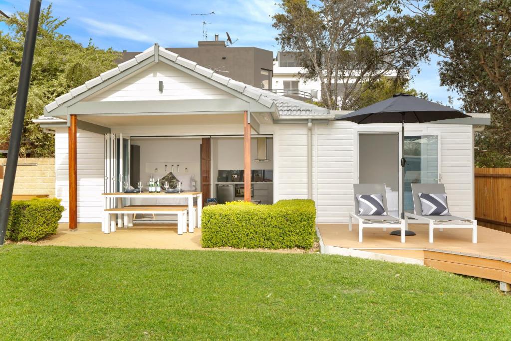 uma casa branca com uma mesa e cadeiras e um guarda-sol em The Beach House North Wollongong em Wollongong