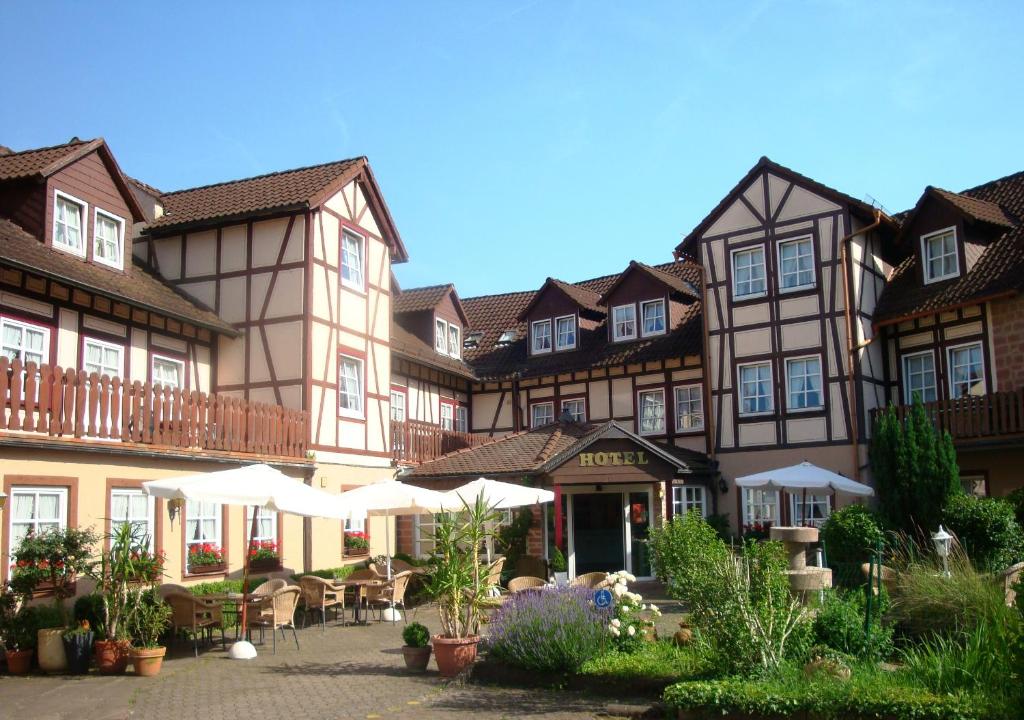 un bâtiment avec des tables et des chaises dans une cour dans l'établissement Hotel Burg-Mühle, à Gelnhausen