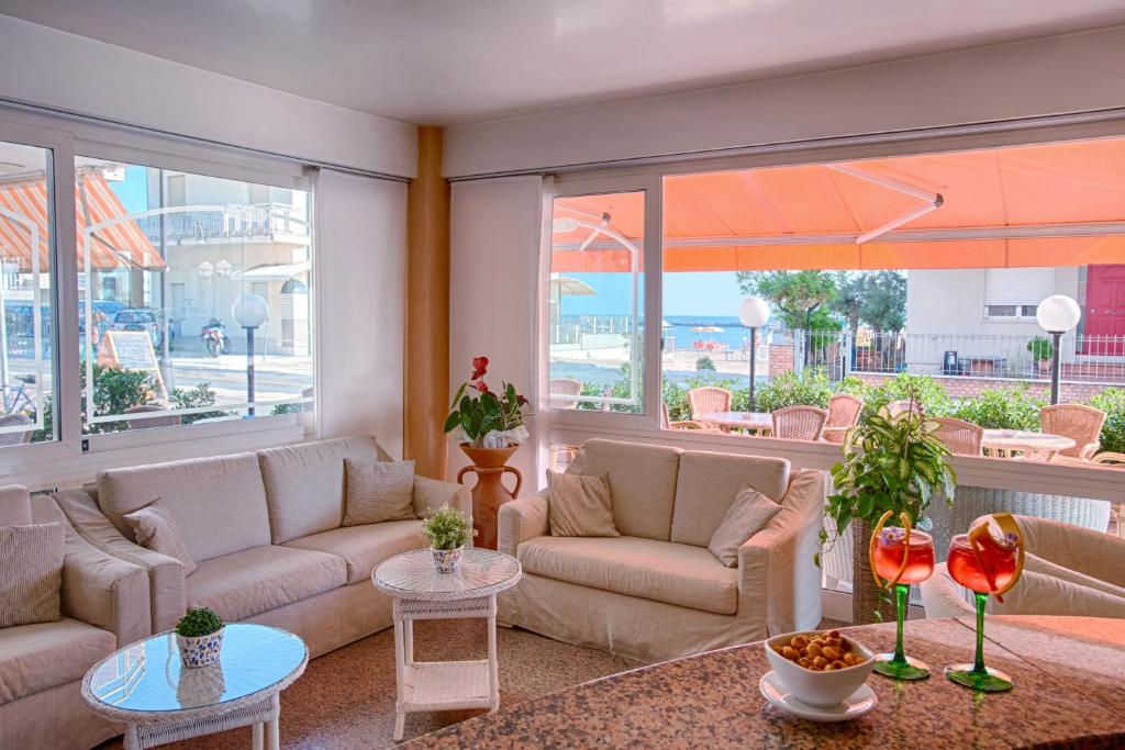 a living room with couches and tables and windows at Hotel Barca D'Oro in Bellaria-Igea Marina