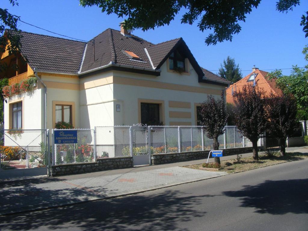 una casa blanca con una valla en una calle en Napfény Apartmanház en Eger