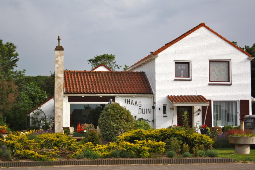 Ein weißes Haus mit einem Schild, auf dem steht: in der Unterkunft Villa 't Haasduin in Wijk aan Zee