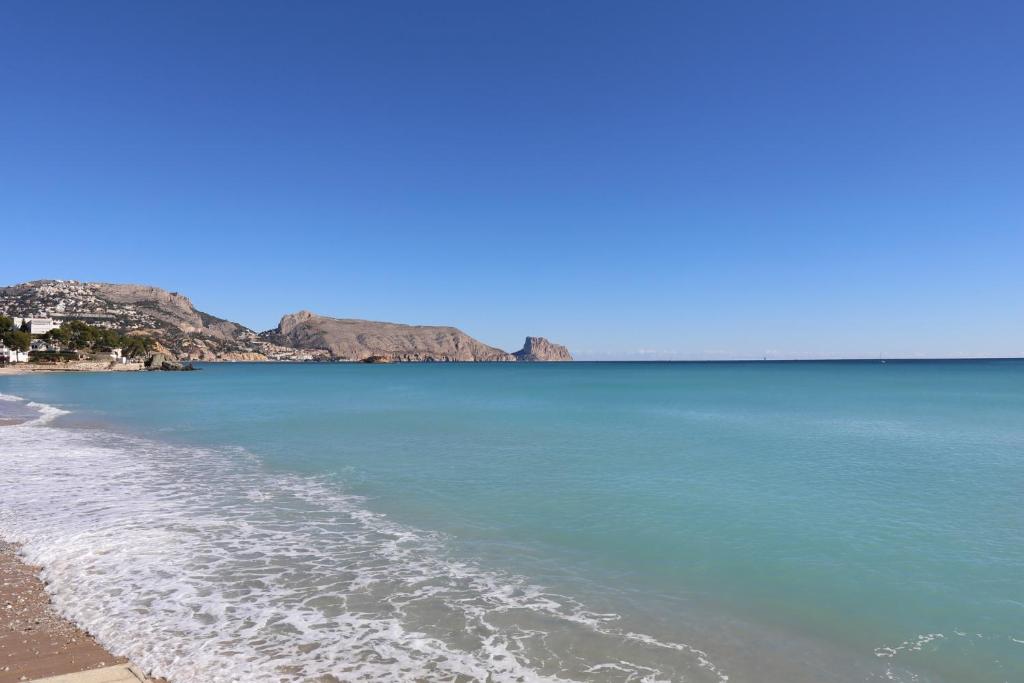 a beach with blue water and mountains in the background at Alteasol playa in Altea