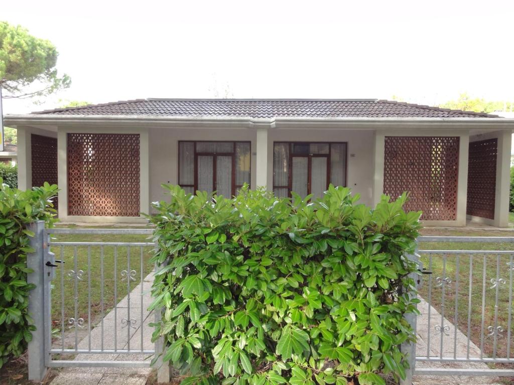 una casa con un cancello e un cespuglio di Villa Regina a Bibione