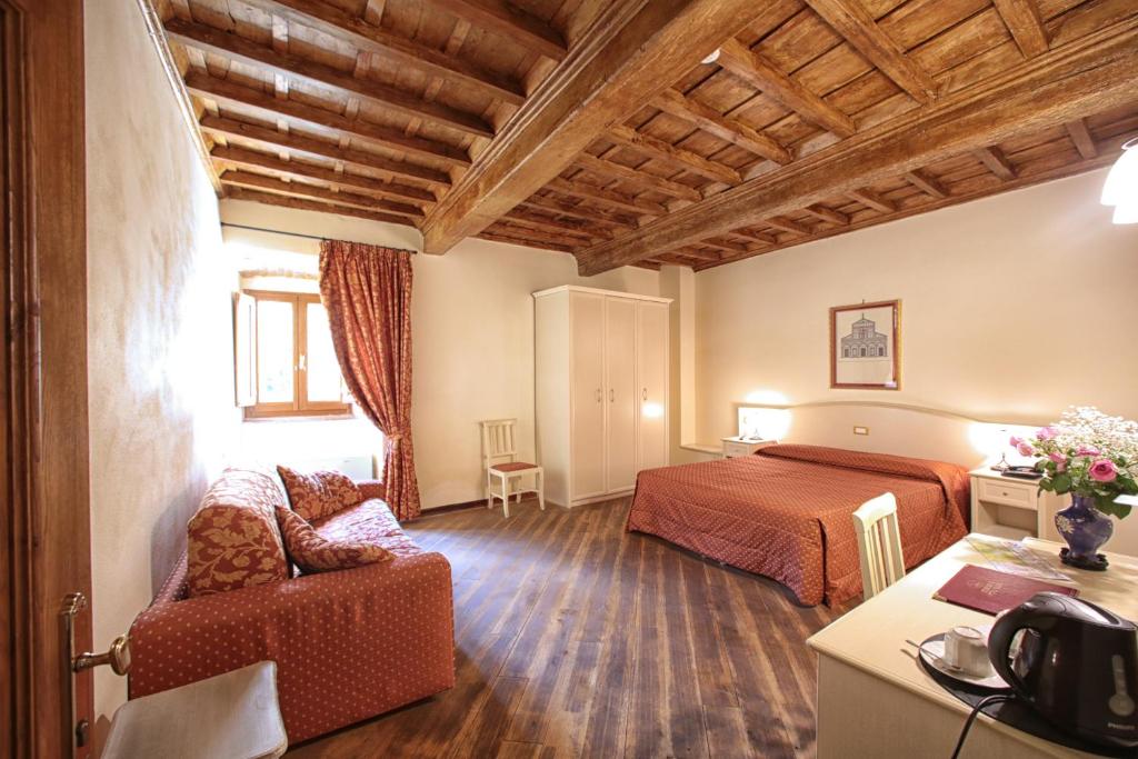 カルミニャーノにあるHotel Villa San Micheleのベッドとソファ付きのホテルルーム